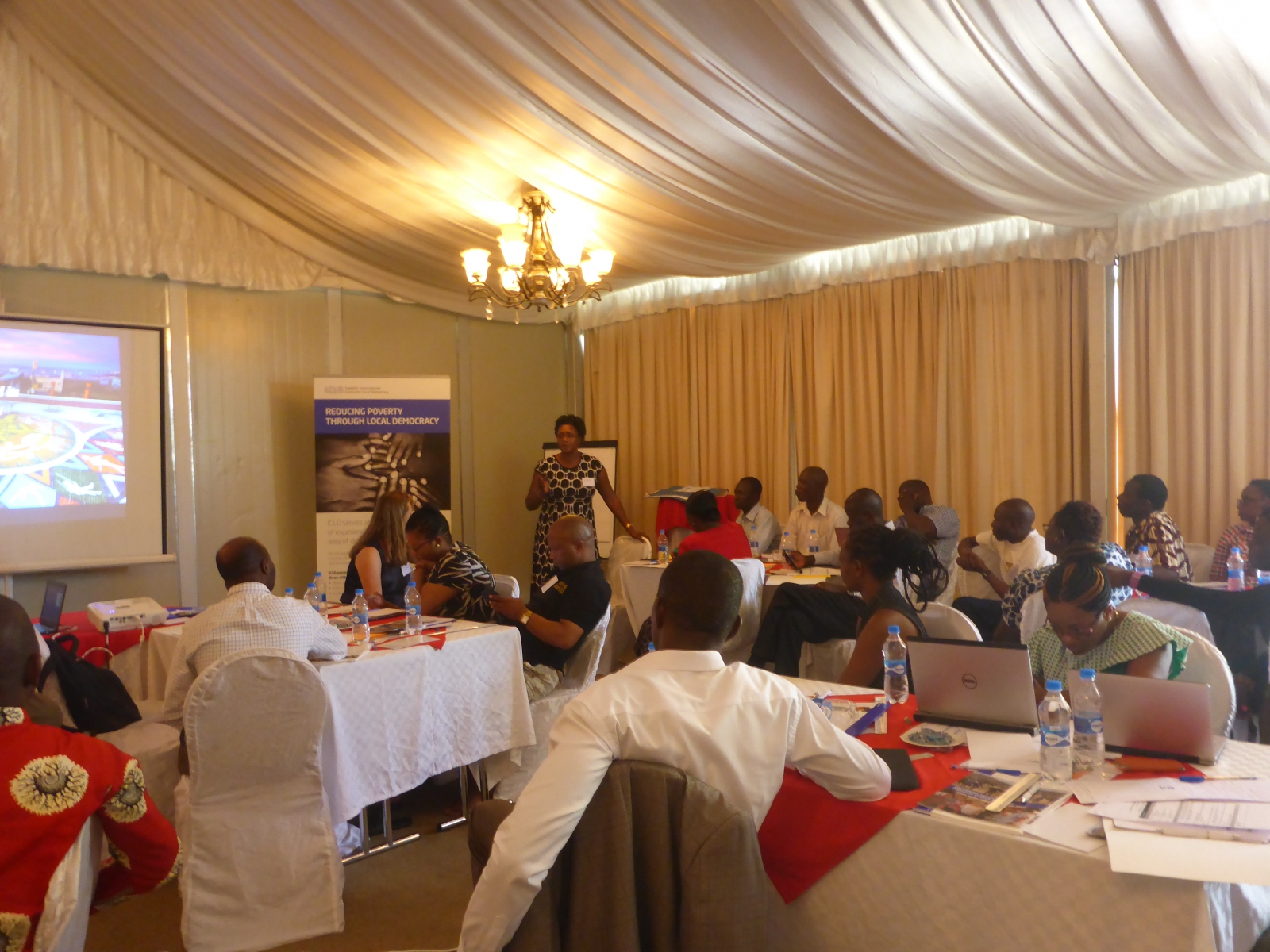 Men and women gathered togheter at a workshop in a big room.