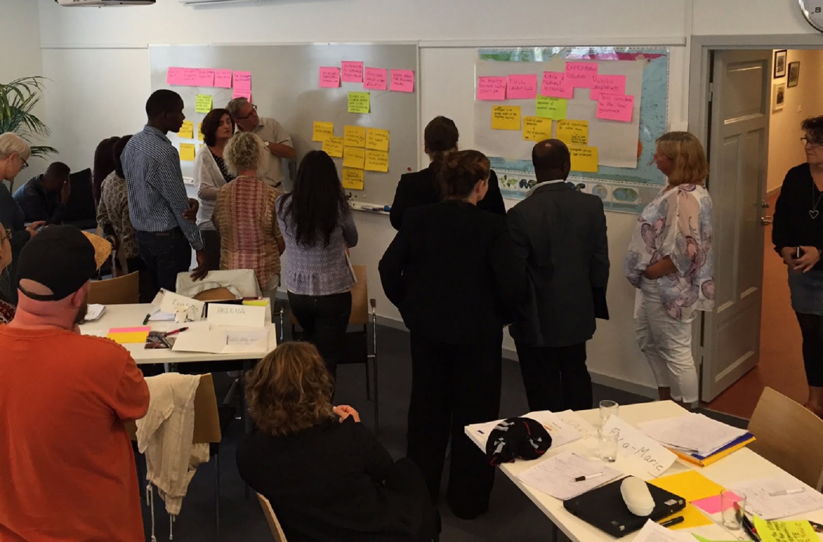 people standing analysing their problem trees on post its on wall in conference room